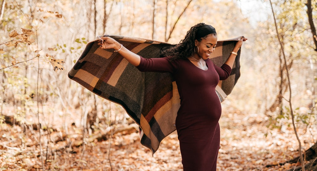 Moda gestante: Mulher negra grávida com manta e vestido manga longa.