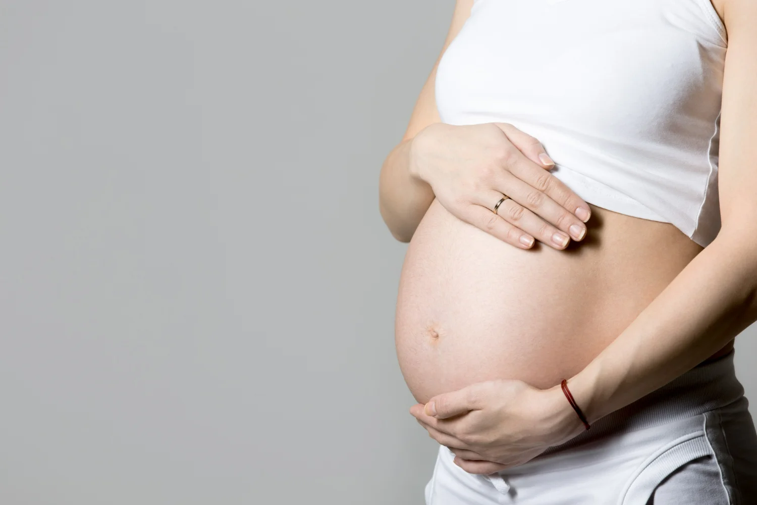 Mulher grávida com as mãos na barriga, representando a contração de treinamento