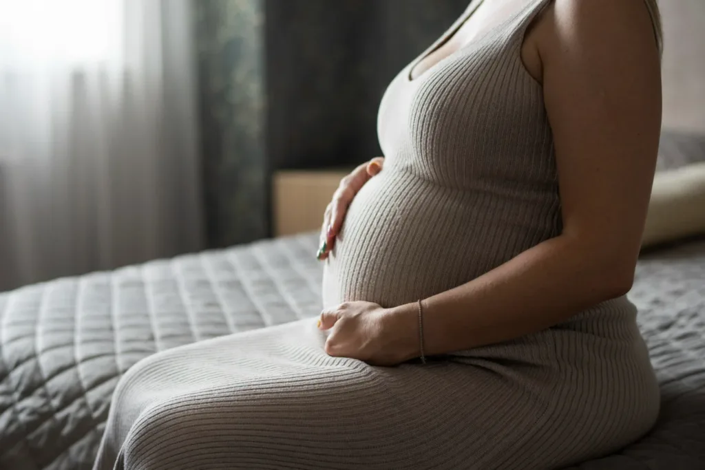 mulher sentada, com as mãos na barriga, em estágio avançado da gravidez