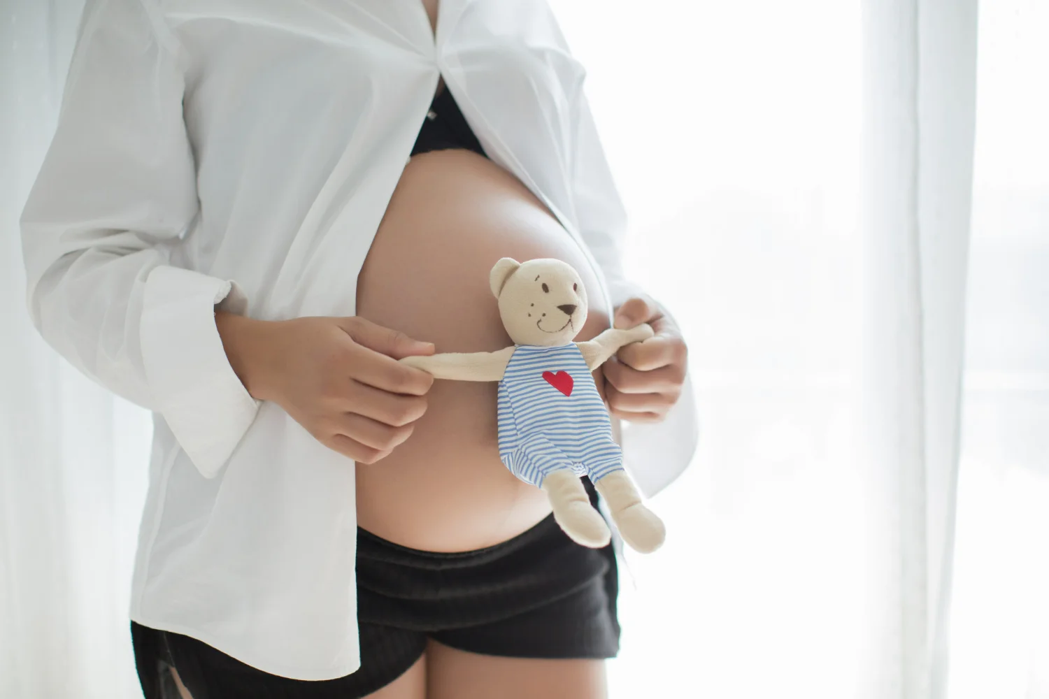 Mulher grávida segurando ursinho de pelúcia após descobrir que seu sangramento na gravidez é normal