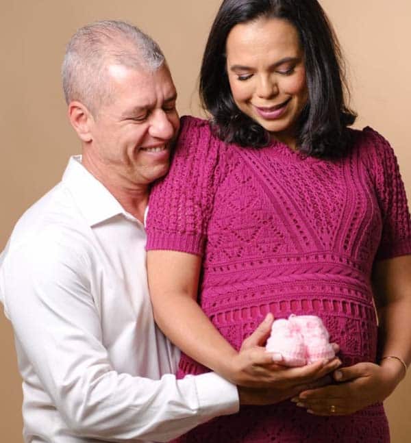 Marido esposa grávida segurando sapatinho de menina.